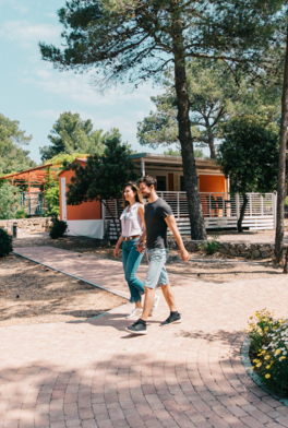 Guests walking through a campsite with mobile homes among pine trees