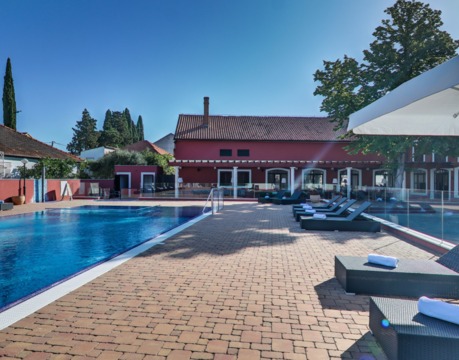 Piscina all’aperto con lettini e ombrelloni nel cortile dell’hotel