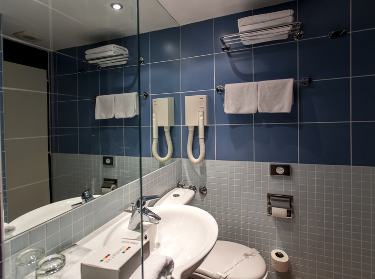 Bagno d’albergo con specchio, lavabo e articoli da toilette