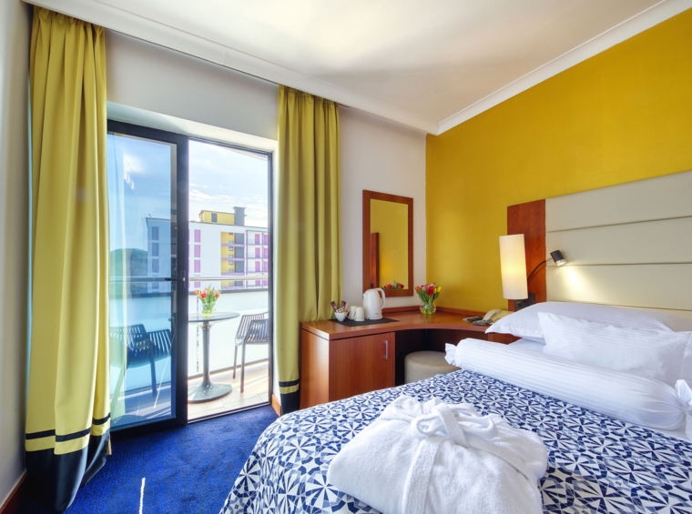 Hotelzimmer mit Doppelbett und Zugang zum Balkon