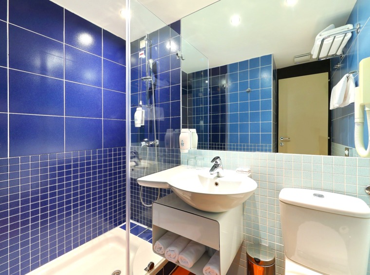 Hotelbad mit blauen Fliesen, Waschbecken und Toilette