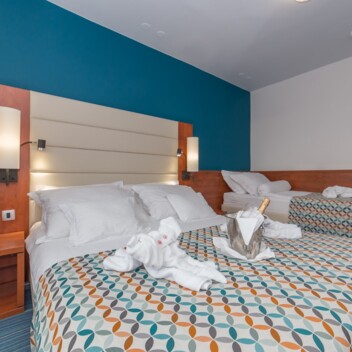 Hotelzimmer mit zwei Betten und dekorativ gefalteten Handtüchern