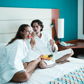 Zwei Personen sitzen auf einem Doppelbett im Hotelzimmer