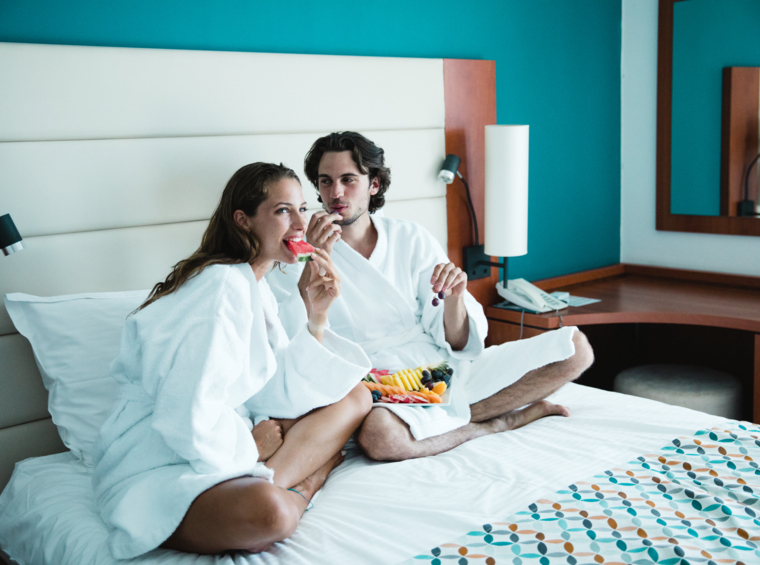 Zwei Personen sitzen auf einem Doppelbett im Hotelzimmer