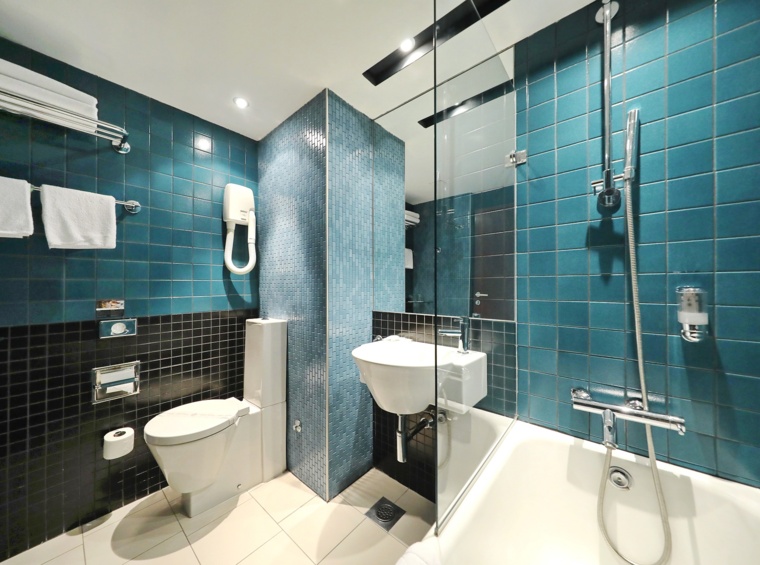 Modern hotel bathroom with blue ceramic tiles, shower and bathtub