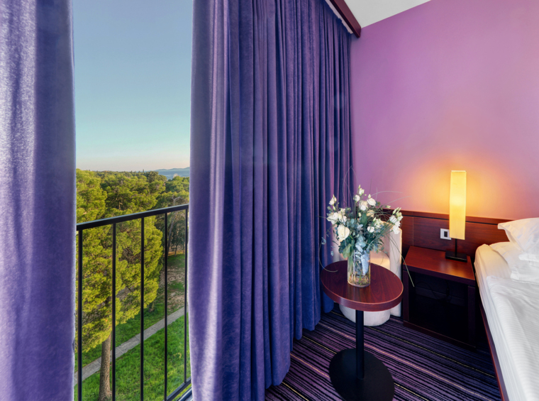 Detalj hotelske sobe s balkonom i pogledom na zelenilo