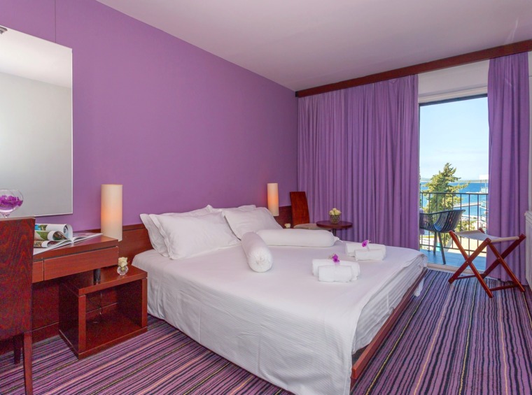 Hotelzimmer mit violetten Wänden und Balkon mit Meerblick