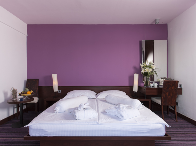 camera d’albergo con letto matrimoniale in tonalità viola