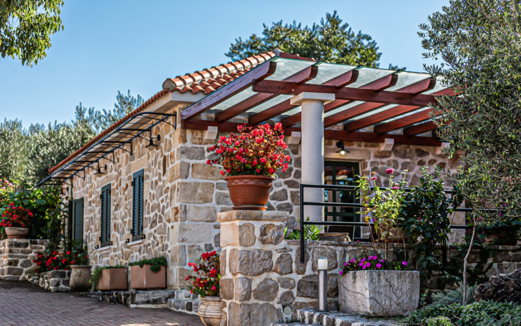 steinhaus mit terrasse und blumen im hof