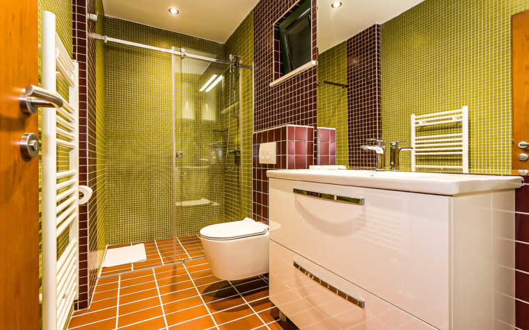 modernes badezimmer mit dusche und waschbecken in grünen und roten fliesen