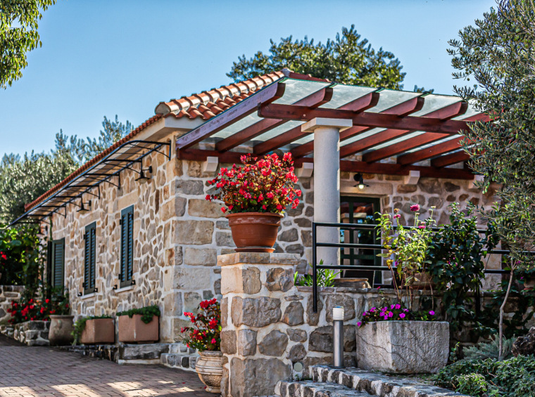 steinhaus mit terrasse und blumen im hof