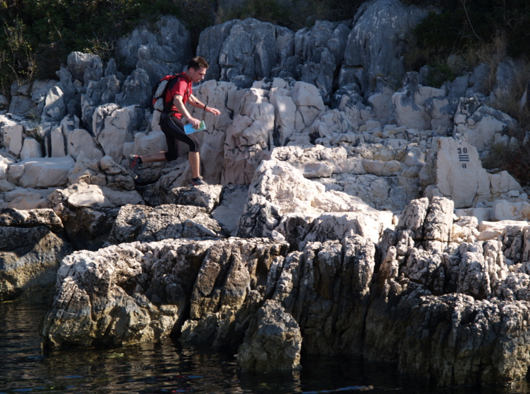 hiker on rocks above the sea