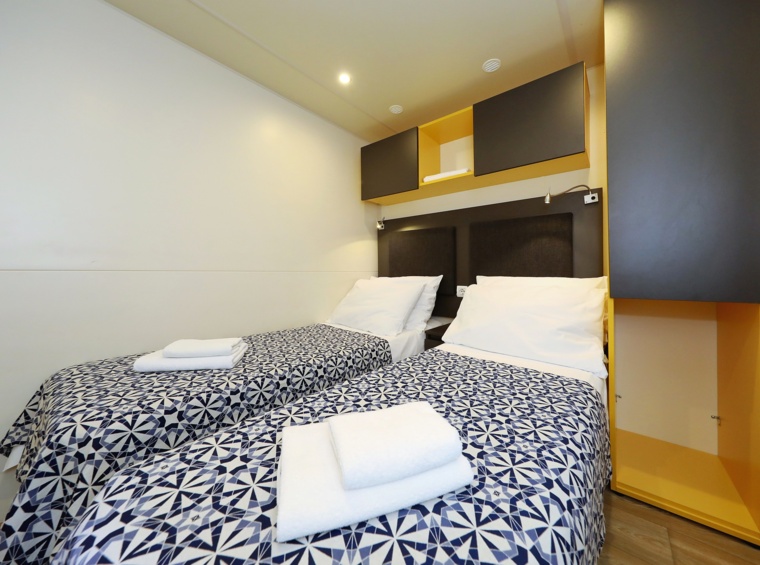 schlafzimmer im mobilheim mit zwei betten und schränken
