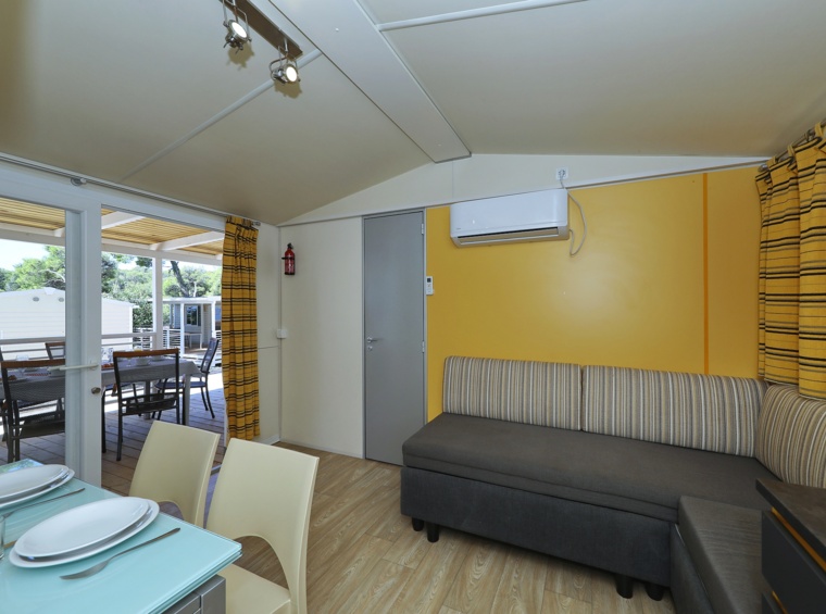 helles Wohnzimmer im Mobilheim mit Essbereich, Sofa und Terrassenzugang