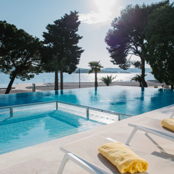 Un uomo e una donna in piedi su una terrazza vicino all’hotel chiacchierano con un drink