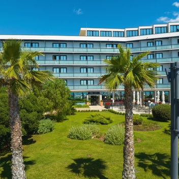 Due persone camminano lungo un sentiero davanti a un edificio alberghiero immerso nel verde
