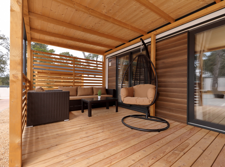 covered wooden terrace of mobile home with lounge furniture and hanging chair