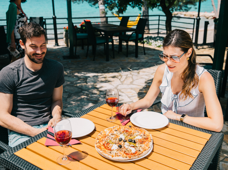 gostje uživajo v pici na terasi restavracije ob morju