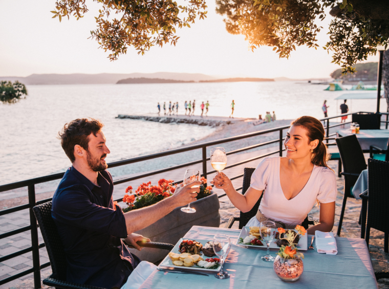 par nazdravlja z vinom ob večerji na terasi ob morju