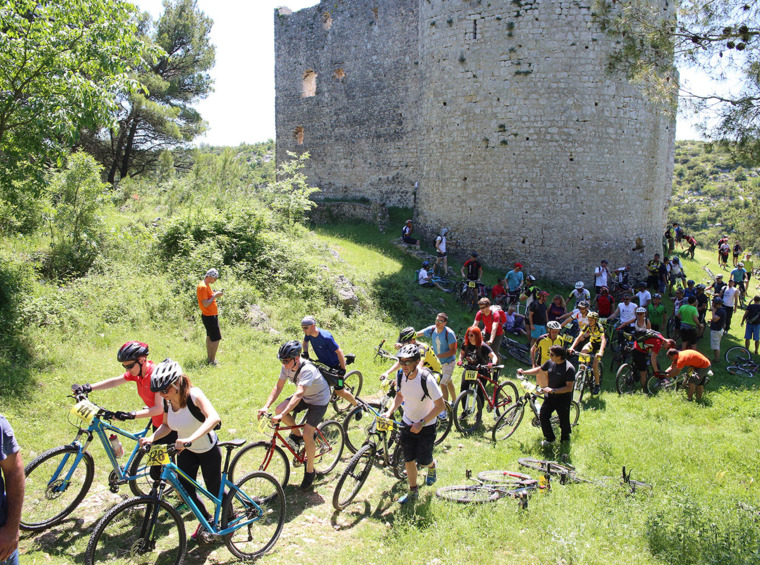 kolesarski dogodek v naravi s skupino udeležencev pri zgodovinski utrdbi