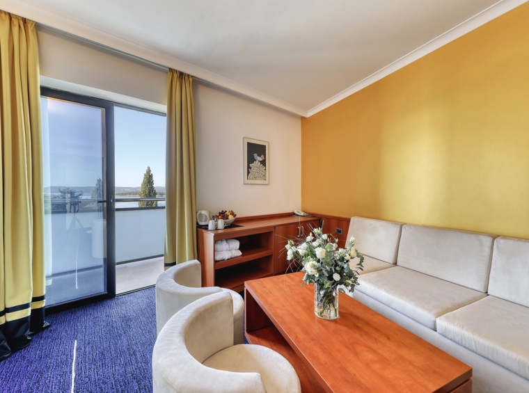 Wohnbereich im Hotelzimmer mit Sofa und Balkonzugang