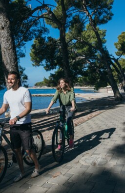 Ein Mann und eine Frau fahren mit dem Fahrrad am Meer durch einen Pinienwald