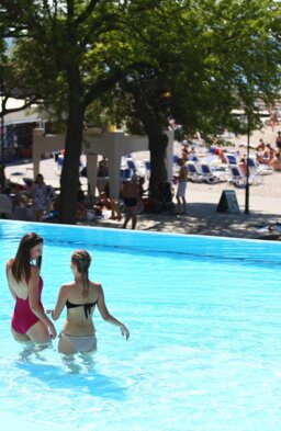 Zwei Frauen gehen durch den flachen Bereich eines Außenpools am Strand