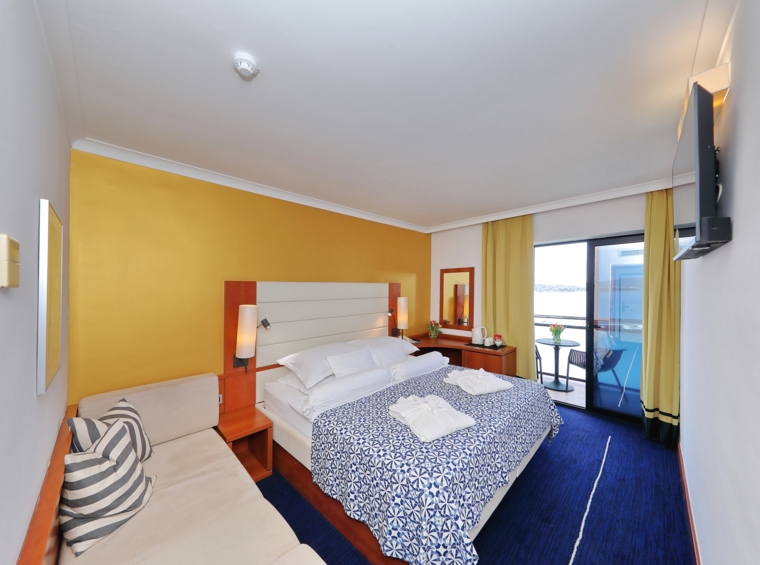 Notranjost hotelske sobe z zakonsko posteljo in sedežnim delom