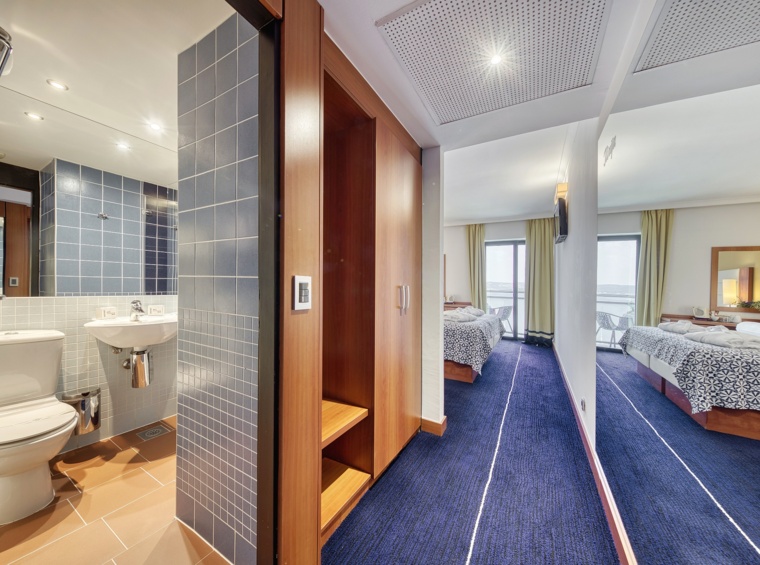 Hotelska kopalnica in hodnik z ogledalom in pogledom proti sobi