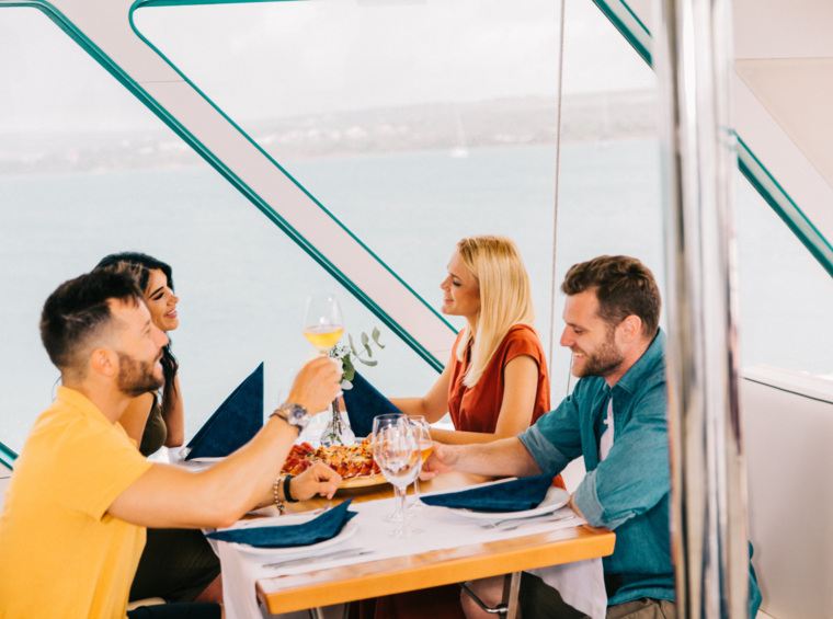 Grupa ljudi nazdravlja za stolom na brodu