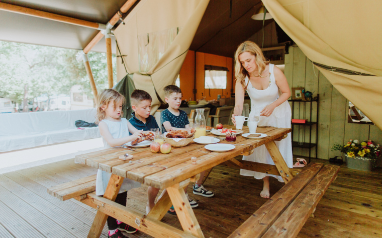 Mama in otroci sedijo za mizo v glamping šotoru