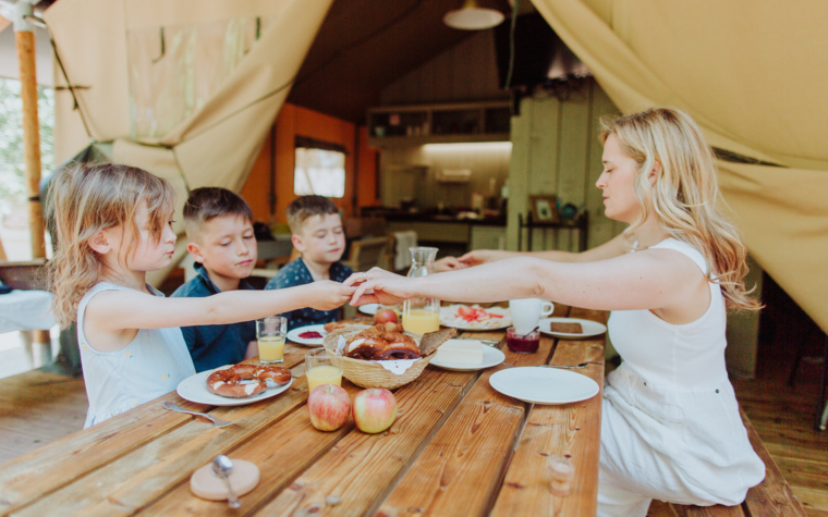 Ženska postreže obrok otrokom za leseno mizo v glamping šotoru