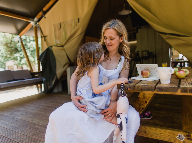 Mother and child sitting at a table inside a glamping tent