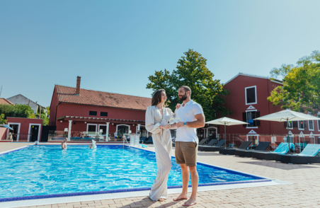Muškarac i žena stoje uz bazen u dvorištu hotela